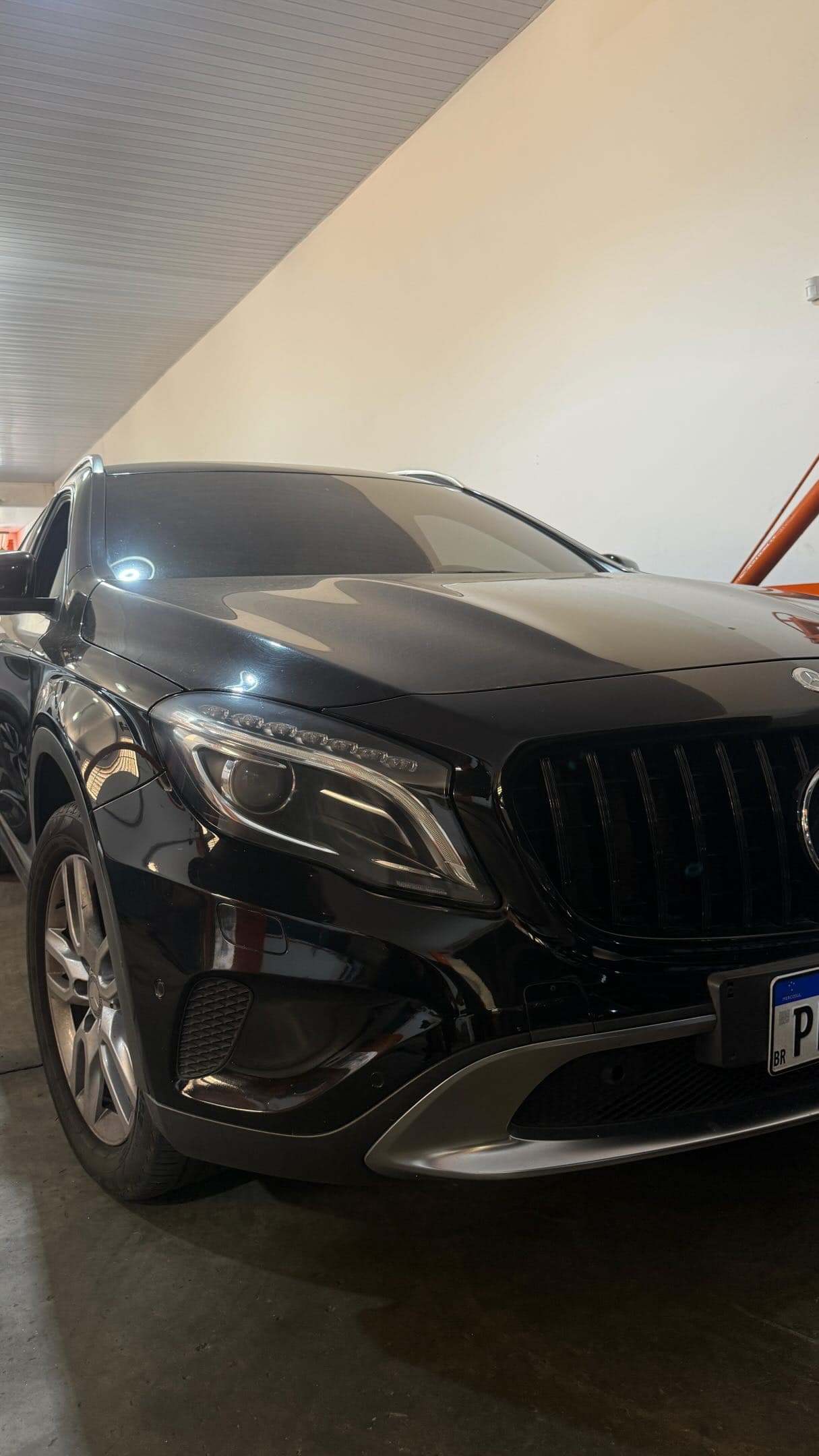 Mercedes GLA preta dentro da oficina, ao lado do elevador laranja